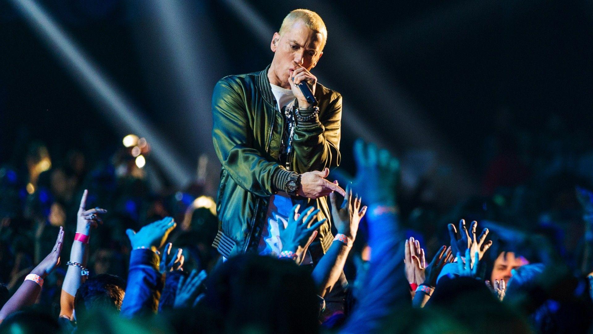 Eminem sings on a stage and his fans raise their hands